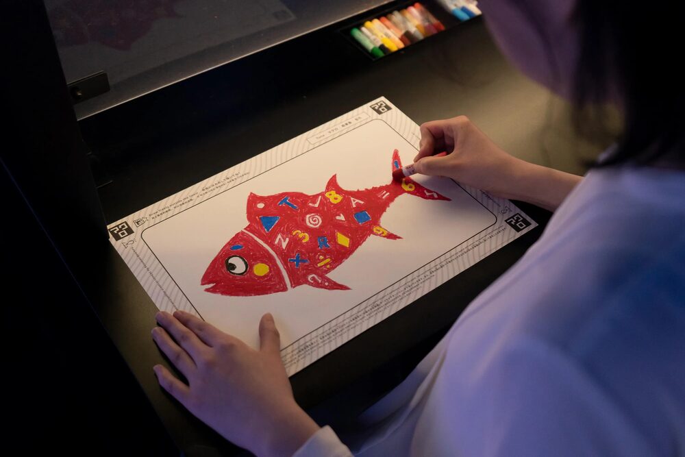 Children colouring paper templates at a scanning station